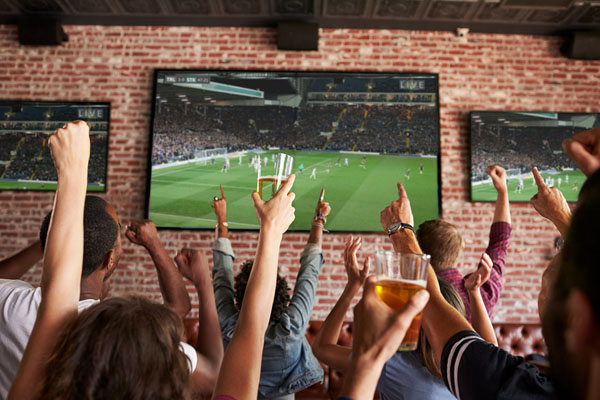 Friends Watching Game In Sports Bar On Screens